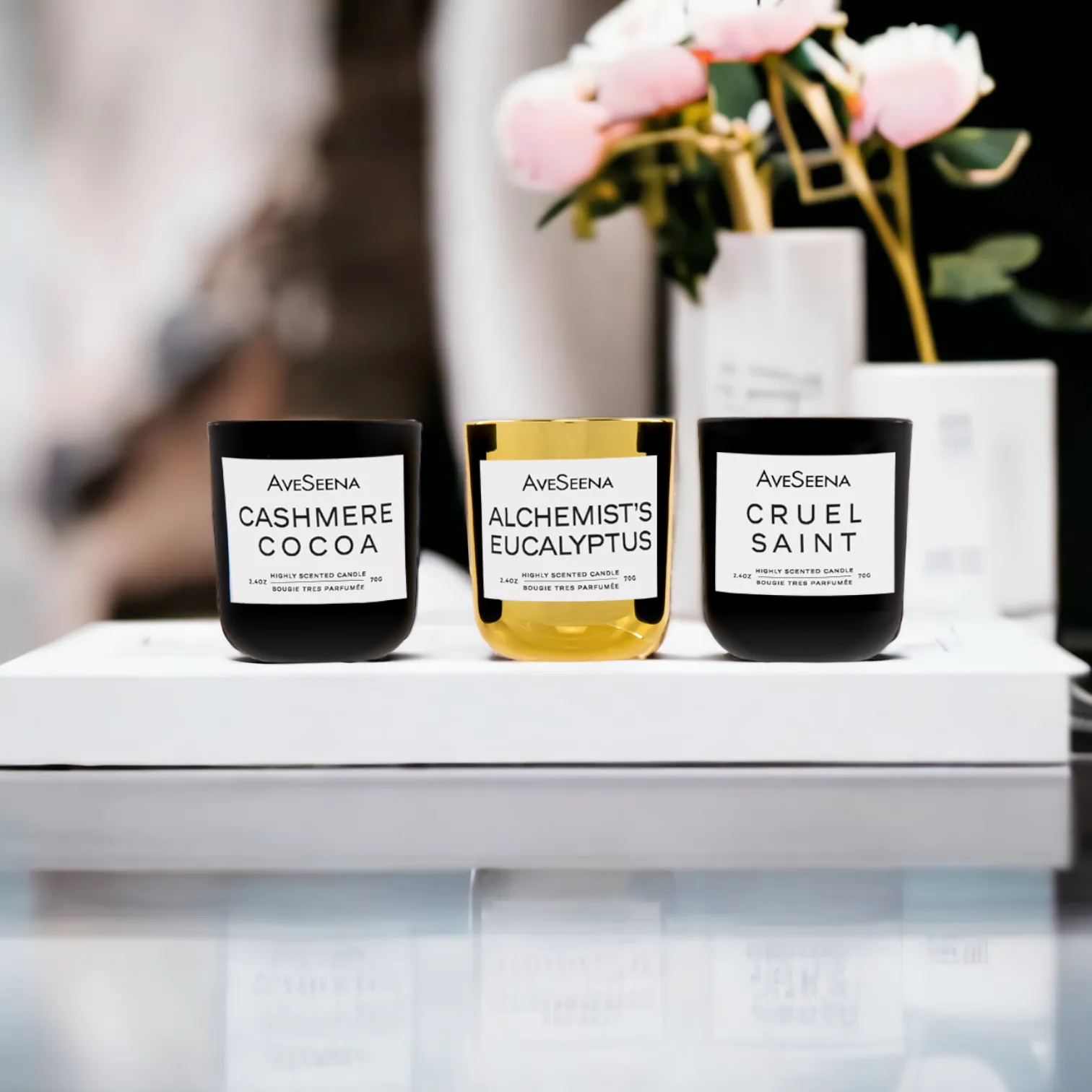 Wellness Trio Gift Candle Set featuring three highly scented votive candles: Cashmere Cocoa, Alchemist's Eucalyptus, and Cruel Saint, presented on a sleek display with soft floral accents.