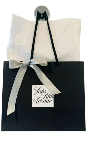 Aveseena saks Saks Fifth Avenue shopping bag with white tissue paper and decorative ribbon, symbolizing luxury retail and the evolving AveSeena and beauty landscape. aveseena in saks 2024