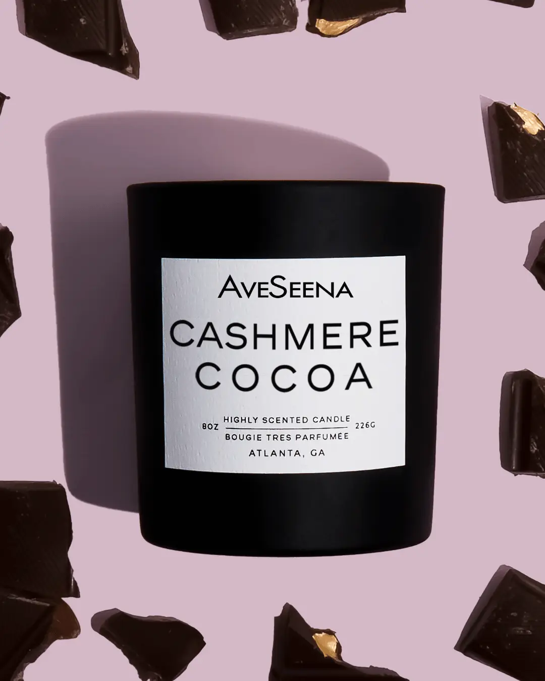 cashmere cocoa candle laying on pink surface with chocolate